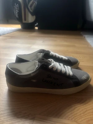 Grå Saint Laurent sneakers - Hej! Säljer dessa väldigt eftertraktade Saint Laurent skorna i storlek 40. Skorna är i väldigt bra skick , box och dustbag medkommer. Bara höra av sig om det är några funderingar.