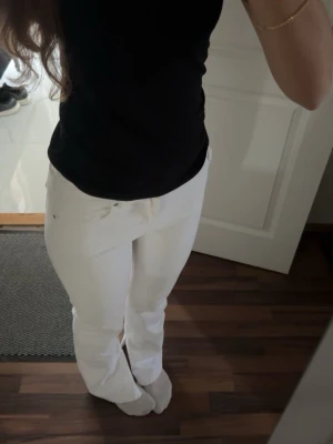 Vita raka jeans - Säljer ett par vita jeans med rak passform och klassisk femficksdesign. Jeansen har normal midja och är tillverkade i ett mjukt denimtyg som sitter snyggt. Perfekta för dig som vill ha en clean och fräsch look.