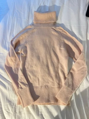 Filippa K stickad tröja i 100% lammull - 100% ull från lamm. Från Filippa K. Använd Max 2 gånger och har knappt noppror. Hög krage. Ljusrosa färg.