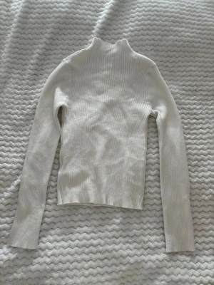 Vit ribbad polotröja från SHEIN - Säljer en vit ribbad stickad polotröja från SHEIN. Tröjan har lång ärm, hög krage och är tillverkad i ett mjukt, stretchigt material. Perfekt att styla med jeans eller kjol för en clean look.
