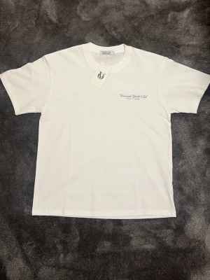 Vit Voronado Yacht Club t-shirt - Snygg vit t-shirt från Voronado Yacht Club med tryck på bröstet och stor yacht-grafik på ryggen. Klassisk passform och rund hals. Perfekt för dig som gillar marina vibbar och enkel stil.