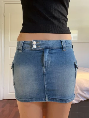 Jeanskjol - Snygg jeanskjol med lågmidja💙Kjolen har två knappar framtill och fina sidofickor med knappar. Midjemått rakt över 30 cm