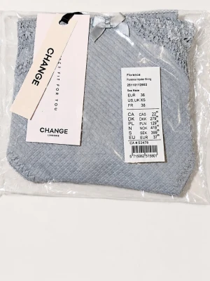 Ljusblå hipster-trosa från Change - Supersöt ljusblå hipster-trosa från Change med diskret rutmönster och spetsdetaljer upptill. Framtill sitter en liten rosett som extra detalj. Nypris: 399kr