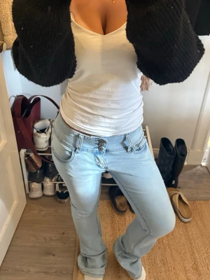 Ljusblå bootcut jeans med tre knappar - Säljer ett par ljusblå bootcut jeans med dubbla knappar i midjan och klassiska fem fickor. Jeansen har en snygg tvätt och markerade sömmar som ger en trendig look. Använt två gånger så är i helt nytt skick. 
