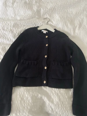 Marinblå stickad kofta med fickor - Säljer denna superfina marinblåa kofta från Gina Tricot i storlek 134/140. Stickad kofta med dekorativa guldknappar framtill samt med små fickor där fram. Skriv vid intresse eller frågor! 