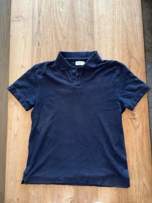 Mörkblå piké - Snygg mörkblå pikétröja från These Glory Days. Tillverkad i bomull, nypris runt 800kr. Skulle uppskatta storleken lite närmre xs-hållet. Om du har några frågor om tröjans mått eller liknande så är det bara att höra av sig!