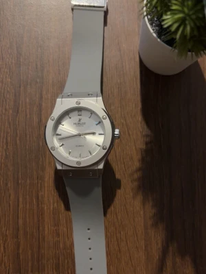 Klocka  - Stilren klockamed silverfärgat ur och matchande grått silikonband. Urtavlan är enkel och elegant med tydliga markeringar och metalliska detaljer. Perfekt accessoar för dig som gillar en clean look.