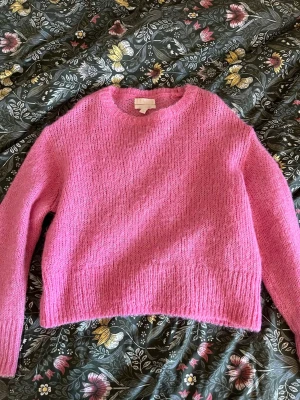 Rosa stickad tröja i ull/alpacka - Mysig rosa stickad tröja i en blandning av ull och alpacka. Tröjan har en avslappnad passform, rund halsringning och långa ärmar. Perfekt för att hålla värmen under kyliga dagar och ger en trendig look till din outfit. Säljer då den inte har kommit till någon användning🩷