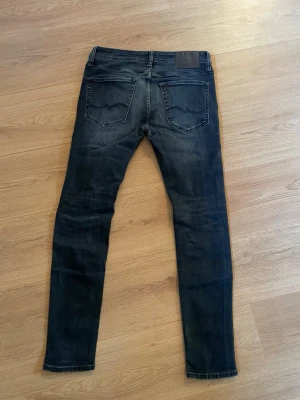 Mörkblå jeans från Jack & Jones  - Säljer ett par mörkblå  jeans från Jack & Jones med klassisk femficksmodell och snygga slitningar framtill. Jeansen har en smal passform och perfekta för dig som gillar en modern och stilren look.