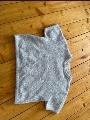Grå stickad tröja Gina Tricot - Mysig grå stickad tröja från Gina Tricot med korta ärmar. I storlek 134-140🥰