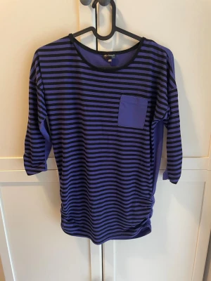 Randig lila och svart t-shirt  - En randig lila och svart randig tröja från KappAhl i väldigt gott skick. Passar väldigt bra till någon med lite alternativ stil enligt mig.