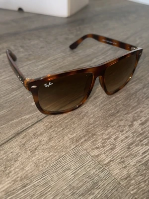 leopard Boyfriend solglasögon Ray-Ban - Snygga Boyfriend solglasögon från Ray-Ban med brunmelerad båge och klassisk form. Glasen är mörka och ger ett coolt intryck. Perfekta för att lyfta din stil under soliga dagar.