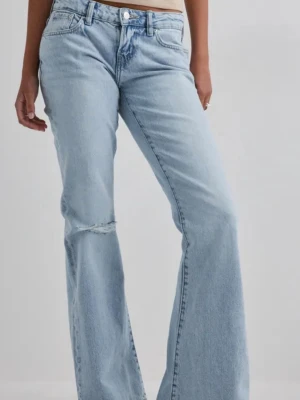 Gina tricot, Ljusblå bootcut jeans med slitning - Säljer ett par ljusblå bootcut jeans med låg midja och en liten slitning på ena knät. Jeansen har klassiska fem fickor och stängs med dragkedja och knapp. Tillverkade i denim med en avslappnad passform och lite utsvänga ben. Storleken är 42. Helt oanvända! Nypris: 499kr 