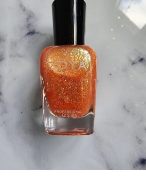 Zoya Professional Lacquer nagellack i färgen Jesy (ZP740) - Nagellack från Zoya i en intensiv orange nyans med massor av guldglittrande skimmer. Kommer i en klassisk glasflaska med svart lock och rymmer 15 ml. Perfekt för dig som vill ha extra bling på naglarna.