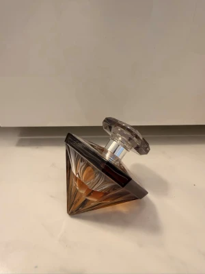 Lancôme La Nuit Trésor L’Eau de Parfum Caresse 50 ml - Säljer min Lancôme La Nuit Trésor L’Eau de Parfum Caresse, 50 ml. Doften är varm, feminin och söt med en mjukare känsla än originalet.  Flaskan är använd, se bilder för mängd kvar. Säljes utan kartong. Fin flaska och kork, normalt bruksskick.  Detta är en äldre/utgången variant som kan vara svårare att få tag på.  Pris: 399 kr prutbart Kan skickas mot frakt eller hämtas enligt överenskommelse.