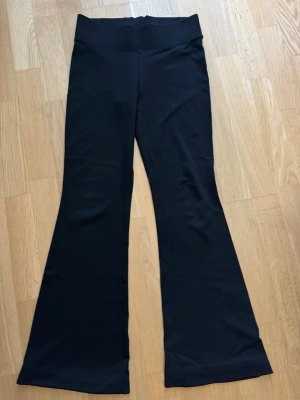 Svarta utsvängda leggings Gina Tricot - Svarta leggings från Gina Tricot med utsvängda ben och hög midja. Stretchigt material som sitter skönt och följer kroppen. Perfekta för en trendig och avslappnad stil.