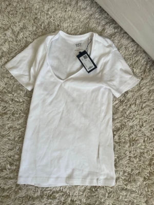 Vit v-ringad topp från 157 i nytt skick - Klassisk vit v-ringad topp från 157 i mjuk bomullsblandning med 3% elastan för extra stretch. T-shirten har korta ärmar och en enkel, clean design som passar till allt. Perfekt basplagg för din garderob. Nypris 80kr … mitt pris 35kr