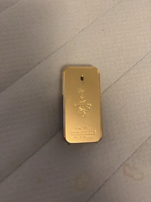 Paco Rabanne 1 Million Parfym - Säljer en ikonisk Paco Rabanne 1 Million parfym i en lyxig guldfärgad flaska som liknar en guldtacka. Flaskan har en rektangulär form med präglad logotyp och text på framsidan. Perfekt för dig som gillar exklusiva dofter och snygg design.