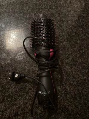 Revlon svart och rosa varmluftsborste - Säljer en svart och rosa varmluftsborste från Revlon. Borsten har ovala borsthuvuden med piggar och är elektrisk med sladd och EU-kontakt. Perfekt för att styla och torka håret samtidigt. Tillverkad i plast och metall.