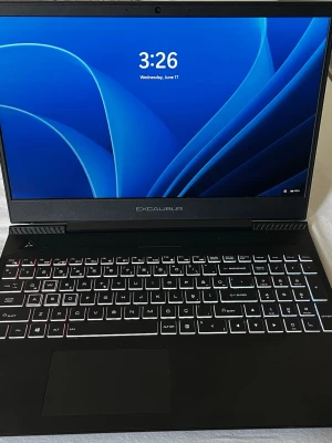 Excalibur gaming laptop - Snygg svart bärbar dator från Casper Excalibur med bakgrundsbelyst tangentbord och stilren design. Skärmen har tunna kanter och datorn har en robust känsla med mattsvart finish. Perfekt för gaming, studier eller jobb. Logotypen syns tydligt på locket.