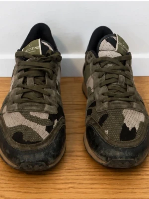 Valentino rockrunners - Säljer ett par snygga sneakers från Valentino med militärgrönt camomönster. Skorna har ovandel i mocka och textil, med svarta och beige detaljer. Klassisk låg modell med snörning och svart hälparti. Perfekta för dig som vill sticka ut med stil.