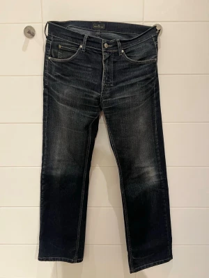 Mörkblå jeans från Jack & Jones - Snygga mörkblå jeans från Jack & Jones med raka ben och klassisk femficksdesign. Jeansen har slitningar och ljusare partier framtill och baktill för en cool, använd look. Tillverkade i denim med tydliga sömmar och logga på bakfickan.