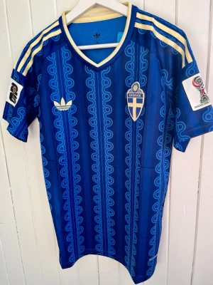 Sverige - VM 2026 - Large - Säljer en svensk blå VM 2026-landslagströja (borta). Tröjan är en reprint i nyskick. Aldrig använd och nyproducerad. VM 2026-patches på ärmen. Inget namn eller nummer på ryggen.  Storlek: Large, men passformen är mer M/L.  Hör av er vid intresse. Kan skickas snabbt eller hämtas i Majorna i Göteborg.  #fifa #WorldCup #panini #fotboll #fifa #WorldCup #panini #fotboll