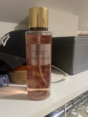 Victoria's Secret Velvet Petals mist - Fräsch body mist från Victoria's Secret i doften Velvet Petals. Flaskan är genomskinlig med rosa vätska och har en guldfärgad kork. Snygg och enkel design som passar perfekt i väskan eller på hyllan.
