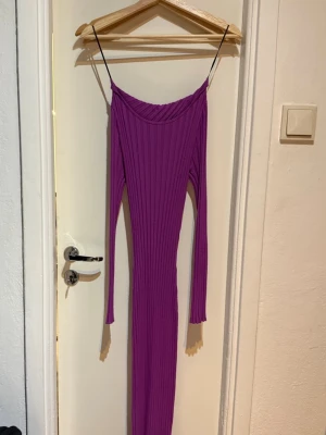 Lila ribbad långklänning H&M - Trendig lila långklänning från H&M med smala axelband och långa ärmar. Klänningen är ribbstickad vilket ger en snygg och kroppsnära passform. Perfekt för dig som vill sticka ut med färg och stil. Materialet är stretchigt och bekvämt.