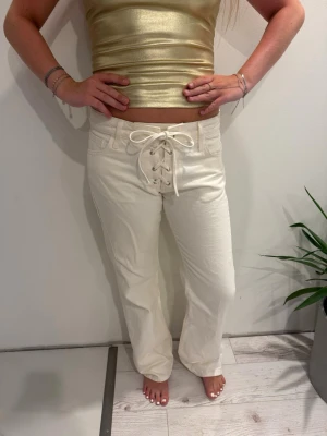 Vita jeans med snörning fram - Säljer ett par vita jeans med unik snörning framtill i midjan. Byxorna har raka ben och klassiska fickor fram och bak. Storlek M men sitter som S!! 