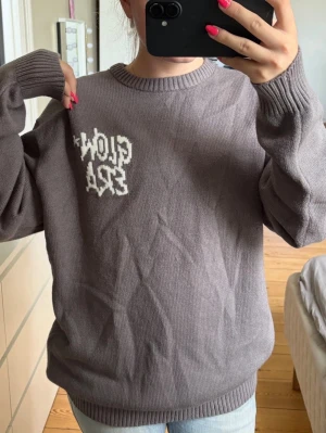 Grå oversized shirt - Säljer en helt ny oversized grå stickad tröja från FB SISTER med texten 'GLOW ERA' i vit graffiti-stil på både fram- och baksidan. Tröjan har rund halsringning, ribbade muddar och är tillverkad i mjukt material. Perfekt för en avslappnad streetwear-look🤩🙌🏼