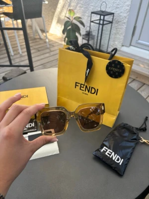 Fendi fyrkantiga solglasögon brun - Snygga solglasögon från Fendi med fyrkantiga bågar i transparent brun plast och mörka glas. Liknar Chimi i modellen. Komplett med låda, originalväska, äkthetscertifikat och originalduk (aldrig öppnad). Sparsamt använda, nästa i nyskick. Nypris 3200kr. 