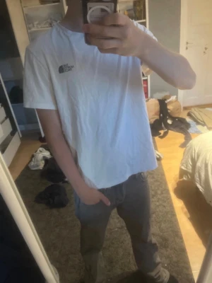 Vit t-shirt från The North Face - Säljer en klassisk vit t-shirt från The North Face med logga på bröstet. T-shirten har rund halsringning och korta ärmar. Perfekt basic-plagg som funkar till det mesta och är riktigt skön att bära.