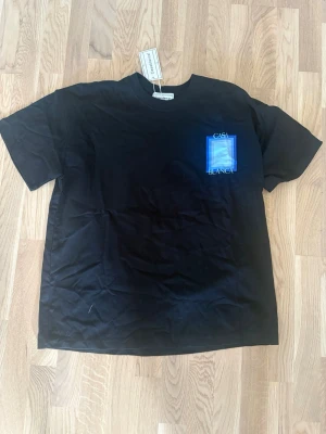 Svart t-shirt från Casablanca - Svart t-shirt från Casablanca med tryck i blått och vitt på bröstet där det står 'Casa Blanca'. Klassisk passform och rund halsringning. Perfekt för en stilren och modern look.