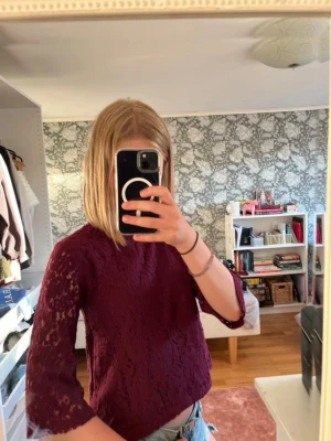 Vinröd spetsblus med trekvartsärm - Vinröd blus i spets med trekvartsärmar och rund halsringning. Blusen har en lätt utsvängd passform och fina spetsdetaljer över hela plagget. Perfekt för dig som vill ha en elegant och trendig topp. Är egentligen för barn så storlek 158 men man kan inte välja barn så jag skrev 34 som inte stämmer