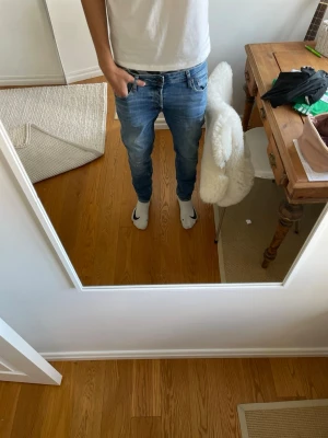 Blå slim fit jeans från Jack & Jones - Säljer ett par blå slim  jeans från Jack & Jones med lätt slitna detaljer. Säljer för ett billigt pris och jeansen passar perfekt året om! Storlek 32/32 j
