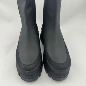 Svarta chunky boots från Palladium - Tuffa svarta boots från Palladium med grov sula på 65mm och elastiska paneler på sidorna. Skorna har dragflikar både fram och bak, samt tydlig logga på sidan. Tillverkade i skinn med robust känsla och modern design. Strl 38 enligt märkning (240mm innermått = mer som en 37) 