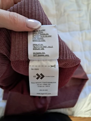 Vinröda seamless tights Lager 157 - Säljer ett par vinröda seamless tights från Lager 157, modell WS Epic Tights Seamless. De har hög midja, ribbade detaljer och är tillverkade i ett stretchigt funktionsmaterial som sitter skönt på kroppen. Perfekta för träning eller chill.