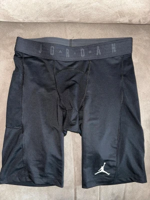 Svarta kompressionstights från Jordan - Säljer ett par svarta kompressionstights från Jordan med tight fit. De har elastisk midja med Jordan-loggan och Jumpman-logga på benet. Perfekta för träning eller basket. Materialet är stretchigt och andas bra.