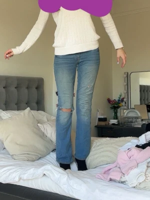 Blå raka jeans med slitningar - Säljer ett par blå jeans flared/bootcut och slitningar vid knät. Jeansen har klassisk femficksmodell och är tillverkade i denim. Perfekta för en avslappnad och trendig look. Jag använder dom tyvärr inte o säljer därför