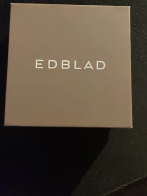 Tvinnad silver halsband från Edblad - Snygg halsband från Edblad i silverfärgat metall med tvinnad design. Halsbandet har en modern och stilren look som passar perfekt för dig som gillar minimalistiska accessoarer. Levereras i original ask.