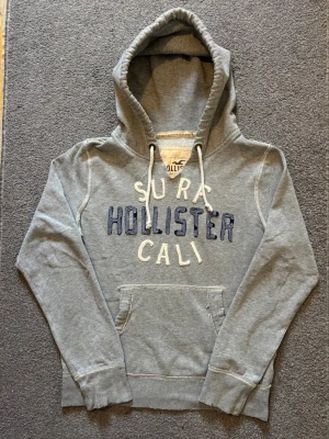 Vintage Hollister Hoodie - Extremt sällsynt och unik Hollister Hoodie med tryck | Hoodien har en unik sliten & distressed design! | Mycket bra skick, (lite smutsig vid högrs ärmen men syns knappast alls, se sista bild)| Storlek S | Längd≈ 65 cm, Bredd 55 cm under armhål-armhåla| Modell 175cm, 68kg | Priset ej hugget i sten! 