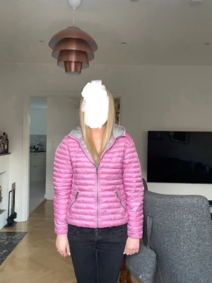 Rosa jacka från Colmar - Säljer en snygg rosa pufferjacka från Colmar med huva och dragkedja framtill. Jackan har två sidofickor med dragkedja och Colmar-logga på ärmen. Lätt vadderad och perfekt för höst och vår. Passar dig som vill ha en färgglad och trendig vinterjacka.