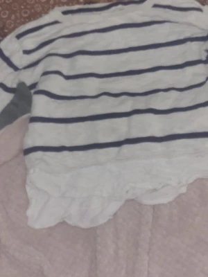 Vit stickad tröja med blå ränder - Säljer en vit stickad tröja med horisontella blå ränder. Tröjan har rund halsringning och långa ärmar. Perfekt för en avslappnad och stilren look. Materialet ser mjukt och bekvämt ut, passar bra till jeans eller kjol.