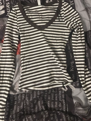 Randig ribbad långärmad topp - Snygg långärmad topp med svart och vit ribbad struktur och bred v-ringning. Toppen har ett randigt mönster och är perfekt för dig som gillar en enkel men trendig stil. Passar till både jeans och kjol.