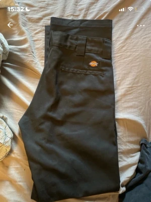 Svarta chinos från Dickies W32/L32 - Säljer ett par svarta chinos från Dickies i modellen W32/L32. Klassisk rak passform med Dickies-logga ovanför bakfickan. Tillverkade i slitstarkt material som är perfekt för en clean och enkel stil. Snygga att matcha med både t-shirt och skjorta.