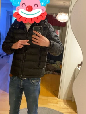 Svart dunjacka från Bvaldi - Säljer en svart dunjacka med huva och dragkedja framtill. Jackan har en puffig design med horisontella sömmar och två sidofickor. Perfekt för kalla vinterdagar och riktigt skön att bära. Passar dig som gillar en stilren och enkel look. (OBS jackan har spild färg på ryggen) Hör av dig om frågor 😊