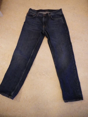 Mörkblå Nudie jeans - Gritty Jackson Blue Soil W31 L30  Säljer ett par riktigt snygga jeans i modellen Jackson Blue Soil. Använda lite men i väldigt bra skick. Perfekt passform och skön kvalitet som funkar till allt.  Riktigt magiska byxor – varje gång jag haft dem på mig har jag fått komplimanger   Storlek: W31 L30 Skick: 8/10 Pris: (200) går att höja och sänka😉