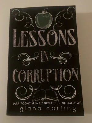 Lessons in Corruption pocketbok - En svart pocketbok med titeln 'Lessons in Corruption' av Giana Darling. Omslaget har kritliknande vit text, en grön äppelsymbol och dekorativa detaljer. Boken är på engelska och har en modern, ungdomlig design.