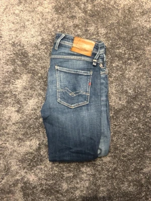 Blå Replay jeans med skinnpatch - Snygga blå jeans från replay med klassisk femficksdesign och skinnpatch bak i midjan. Jeansen har raka ben och tydliga sömmar på bakfickan. Perfekta till en avslappnad streetstil.